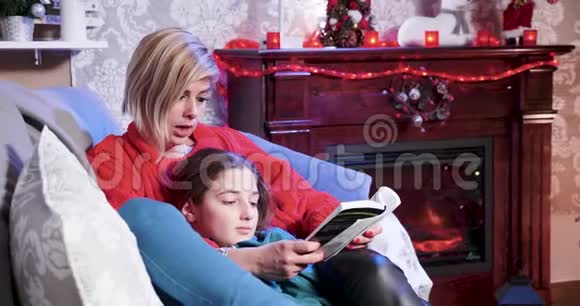 圣诞节那天年轻的母亲在读一本书上的故事视频的预览图