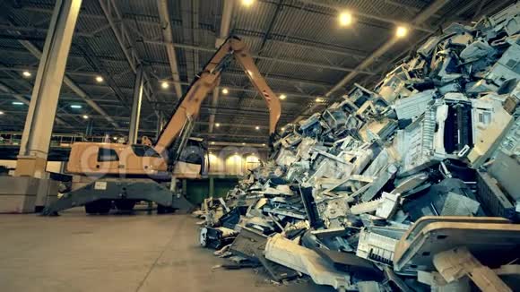 一堆破碎的办公室机器和一台挖掘机站在附近回收行业废旧电子回收工厂视频的预览图