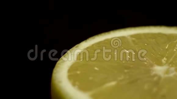 在黑色桌子和黑色背景上关闭旋转新鲜黄色半柠檬的镜头视频的预览图