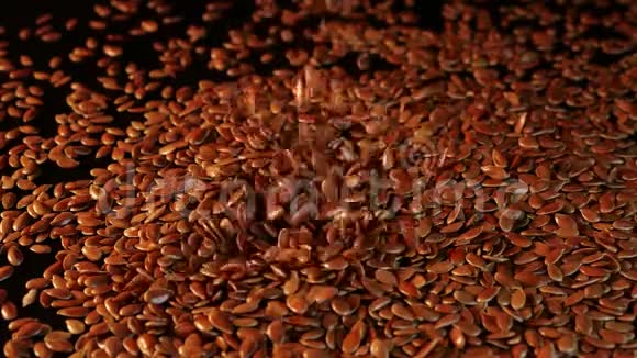 许多亚麻籽从上到下洒在光滑的黑色桌子上在黑暗的背景下亚麻近景视频的预览图
