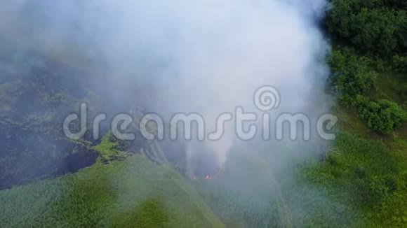 危险的火在靠近森林的草地上俯视从附近的一场大火中射出的浓烟视频的预览图