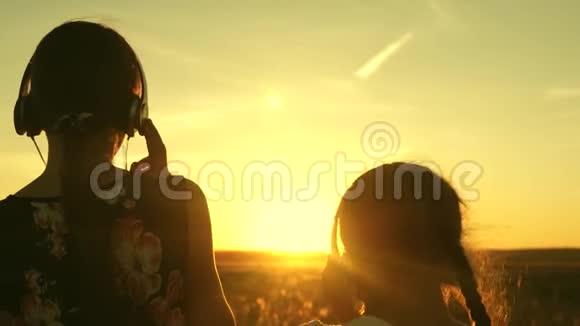 童年概念快乐的少女们在美丽的夕阳下在公园里听音乐儿童视频的预览图