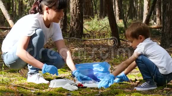 家人母子在树林里收集垃圾放进袋子里抚养儿童爱护环境视频的预览图