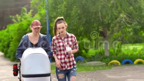 两个女孩和一个孩子在婴儿车里散步视频的预览图