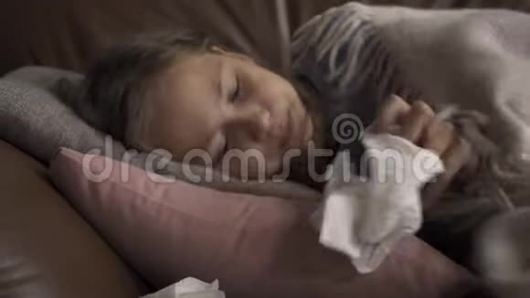 一个生病的年轻白种人女孩在家里躺在毯子下咳嗽和吹鼻子孩子发烧了视频的预览图