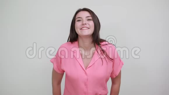 漂亮的白种人年轻女子穿着粉红色的衬衫做着心形的动作有趣视频的预览图