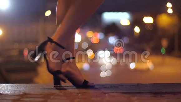 女孩走在公路上的城市桥上穿着漂亮的高跟鞋腿上有高跟鞋特写在傍晚的城市漫步视频的预览图