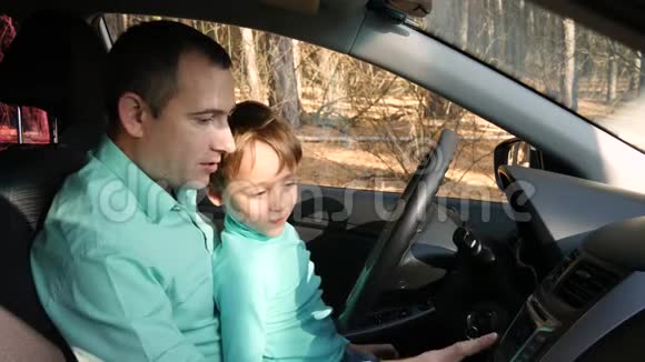一位父亲按按钮让儿子看车里的多媒体父子关系幸福家庭视频的预览图
