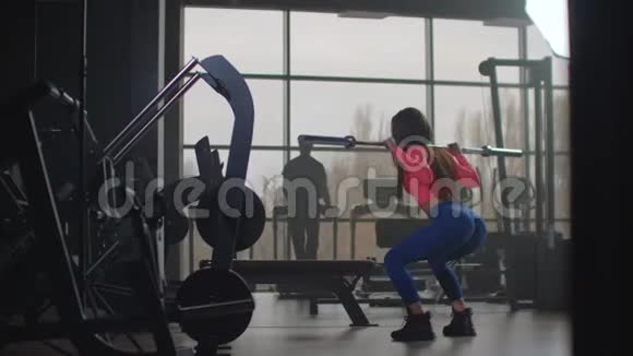 这位女运动员正在健身中心蹲着视频的预览图