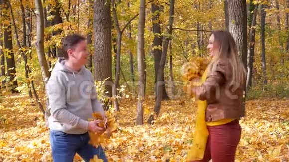 在森林或公园里有黄色叶子和微笑的年轻夫妇视频的预览图
