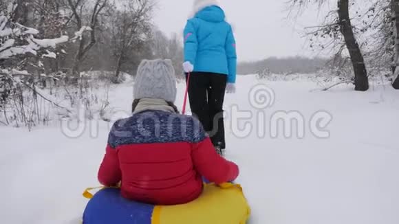 妈妈带着一个快乐的孩子在雪地上的雪橇上圣诞节假期旅行和度假浴缸娱乐视频的预览图
