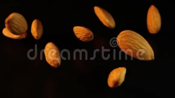 诱人的杏仁落在黑色的背景上一把脆脆的坚果撒在一张深色光滑的桌子上可食用视频的预览图
