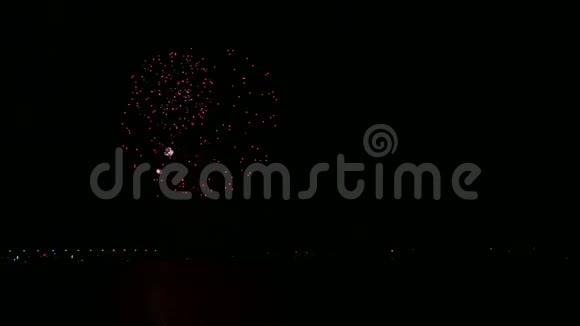 明亮明亮的节日烟花在夜空中映照在水面上视频的预览图