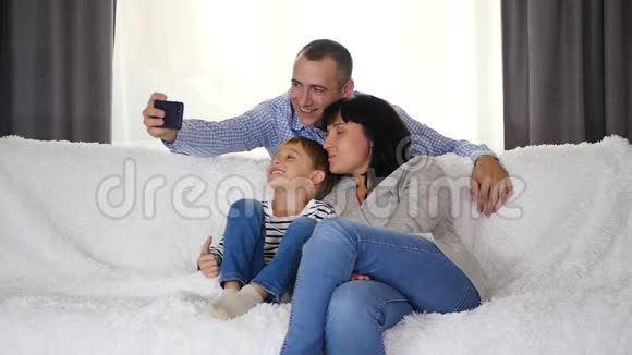 幸福的家庭一起坐在沙发上一位父亲给他的妻子和儿子拍自拍照片技术视频的预览图