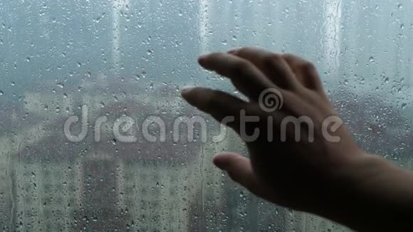 下雨天男用手触摸玻璃窗视频的预览图