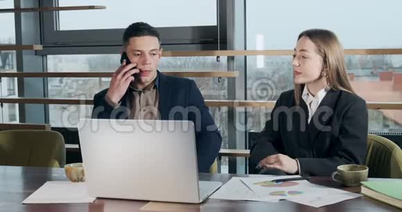 男人说着电话一个女人从旁边看着明亮的现代办公室关切的男女视频的预览图