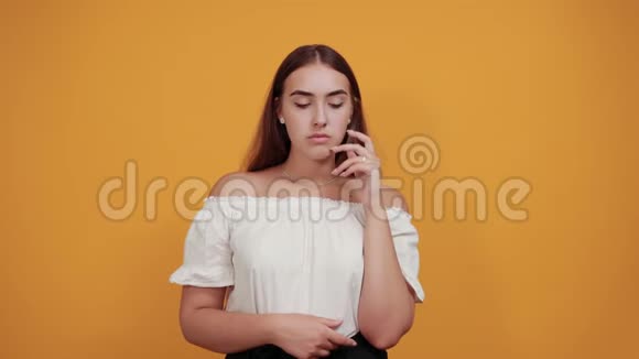 不高兴的年轻女子用手指靠近眼睛在橙色的墙上哭泣视频的预览图