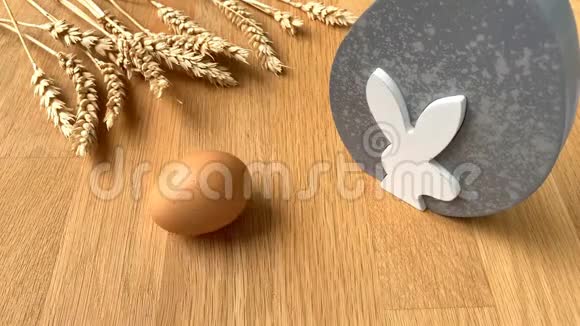 在成熟麦穗的背景下鸡蛋在木桌上旋转复活节的概念视频的预览图