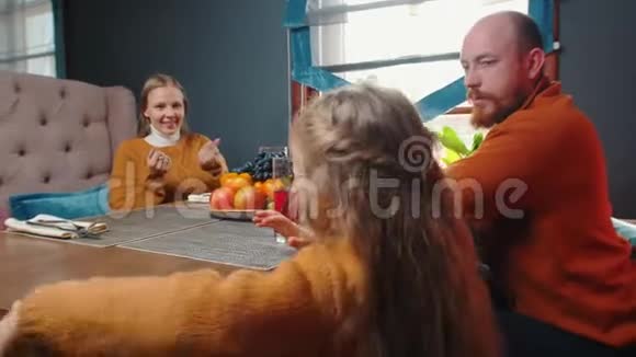 一家人坐在酒店的餐馆里喝果汁一个小女孩坐在她母亲身边拥抱她视频的预览图