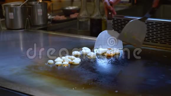 铁板烧厨师在餐厅烹制八爪鱼一个开放的热烤盘视频的预览图