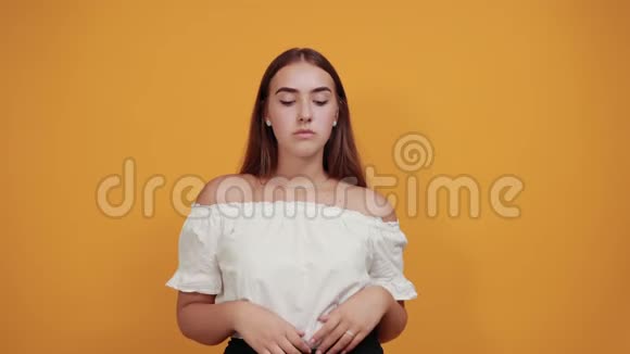 疲惫的年轻女子手牵着头头痛孤立在橙色的墙上视频的预览图