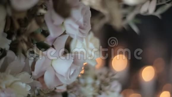 雪白的玫瑰站在花瓶里背景是模糊闪烁的灯光和蜡烛美丽的花朵视频的预览图