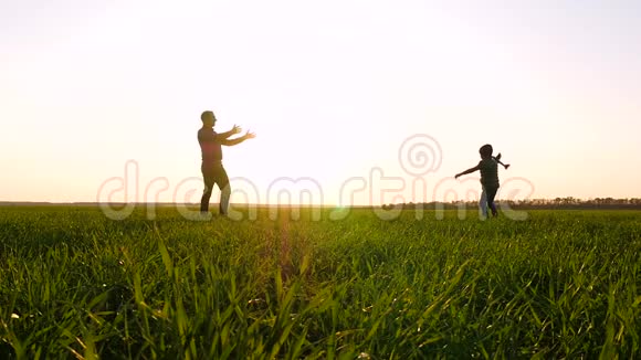 爸爸和孩子在日落的背景下在户外玩耍发射一架玩具飞机进入天空视频的预览图