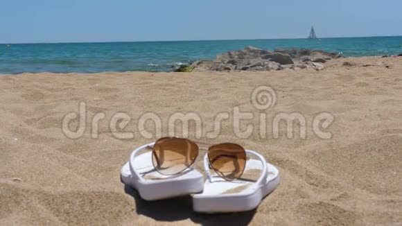 海边沙滩上的女士拖鞋和太阳镜视频的预览图