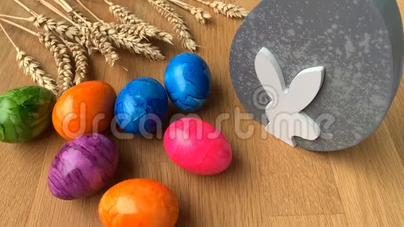彩色彩蛋在一张木桌上旋转背景是成熟的麦穗复活节的概念视频的预览图