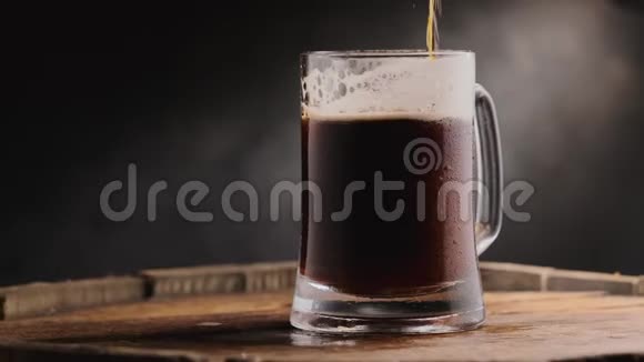 黑色背景下啤酒杯中的冷黑啤酒视频的预览图