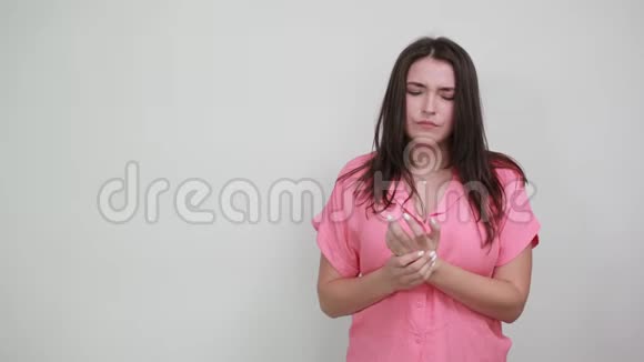 穿着粉红色衬衫的白种人年轻女人在手上做按摩看上去很悲伤视频的预览图