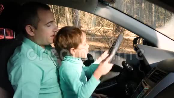 快乐的孩子在车里转动方向盘父亲出示汽车装置家庭教育和汽车的概念视频的预览图