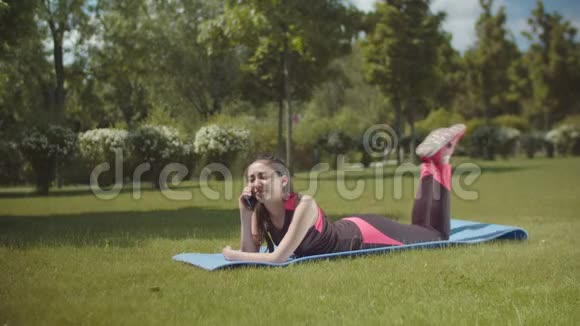 适合的女人在户外躺在垫子上打电话视频的预览图