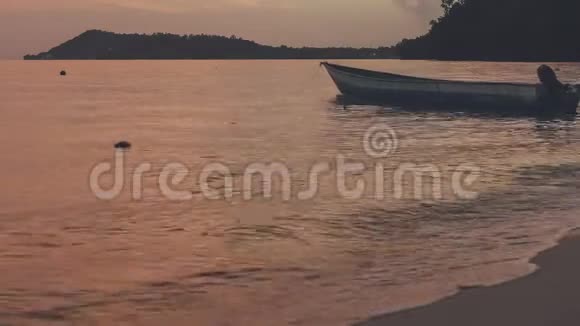 日落时靠近海滩的当地木船在甘姆岛的黄昏平静的海浪在海面上翻滚视频的预览图