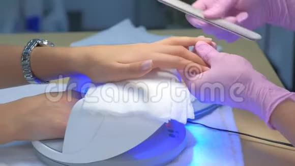 机械抛光客户的指甲使用文件另一只手干燥在紫外线灯视频的预览图