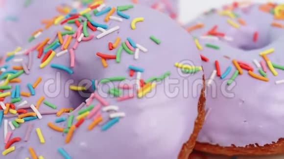 极致特写旋转七彩糖果覆盖紫色糖霜甜甜圈戒指4k龙红相机视频的预览图