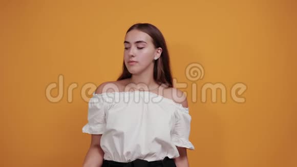 强壮迷人的年轻女子展示肌肉微笑着在橙色的墙上视频的预览图