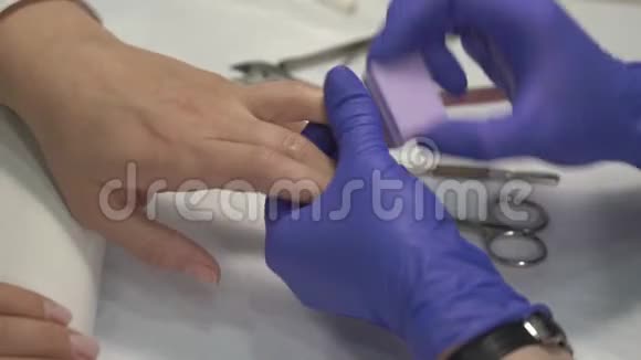专业美甲师在手套上抛光指甲然后涂上清漆视频的预览图
