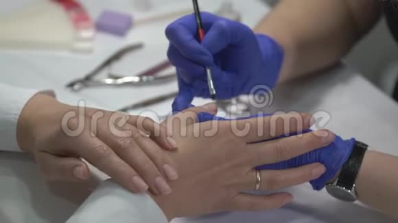 专业的美甲师在手套上覆盖指甲然后用清漆覆盖视频的预览图