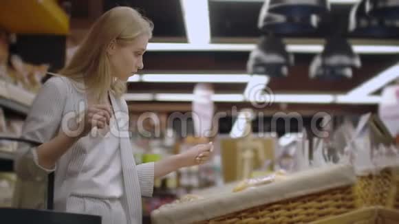 销售购物消费主义和人的概念幸福的年轻女人选择和阅读标签上的面包在市场上视频的预览图
