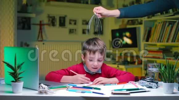 一个男孩坐在学校的桌子旁一只手给他头部按摩视频的预览图