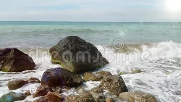 一个小小的海浪在石头上溅起美丽的水花黑海的波浪交替地撞击站立的石头视频的预览图