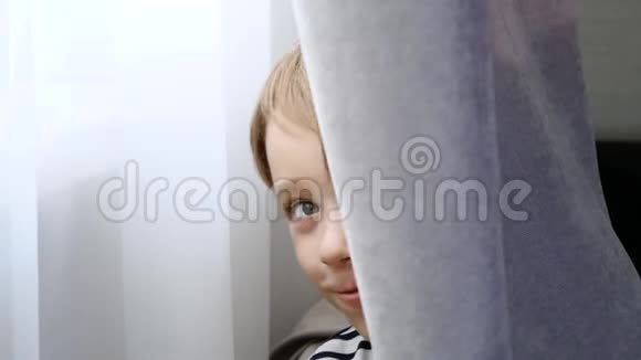 开朗的小男孩玩捉迷藏婴儿从窗帘后面偷看说偷窥视频的预览图