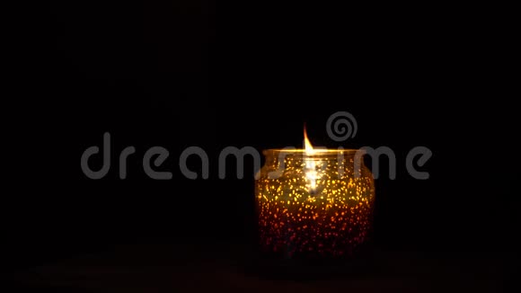 烛台上的蜡烛在黑色背景下燃烧视频的预览图
