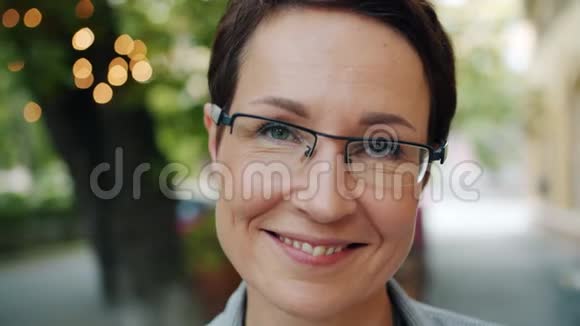 成熟女商人戴着眼镜在室外镜头前微笑的特写肖像视频的预览图