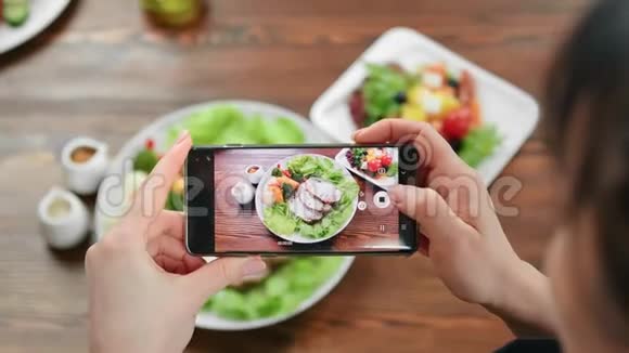 俯视图女性使用智能手机在端盘上拍照食物4K红色相机拍摄视频的预览图