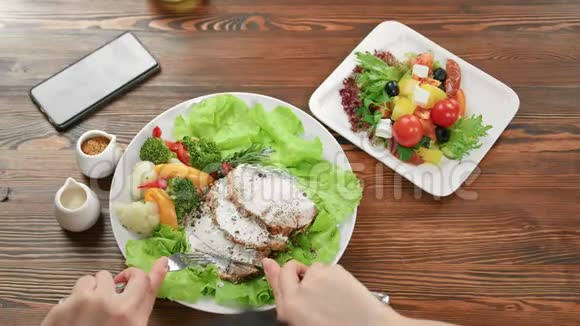 女性手拿叉子和刀子吃鸡肉和蔬菜沙拉4k龙红相机视频的预览图