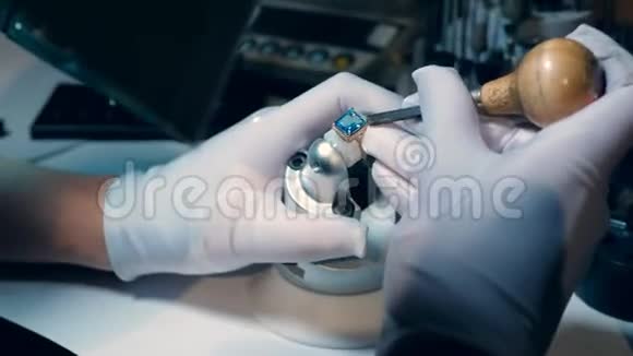 一个珠宝商用一个带蓝色宝石的金戒指工作视频的预览图