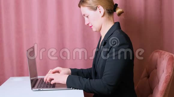 严肃的女秘书坐在工作场所的一张桌子上用笔记本电脑打字视频的预览图