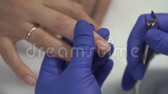 专业的美甲师在手套上剪下指甲上的皮肤然后涂上清漆近距离射击视频的预览图